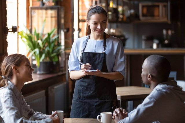 Waitress welcoming restaurant guests take order writing on notep
