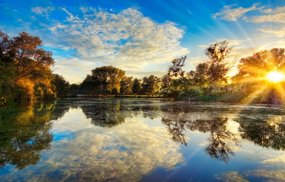 Der abendliche Wolkenhimmel spiegelt sich in einem See im Ostpark in Frankfurt am Main